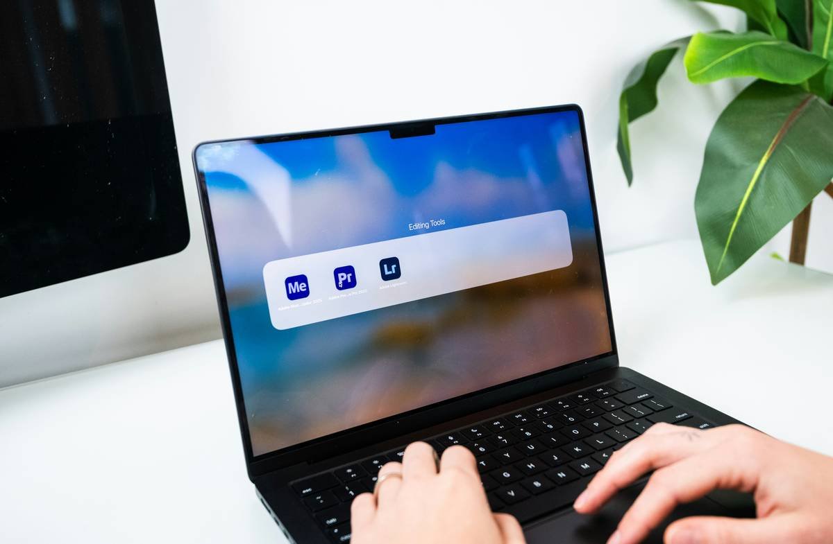 A photo/video editor opening Premiere Pro and Lightroom programs on their laptop computer.