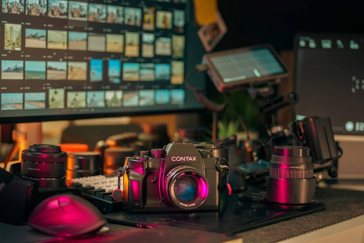 Contax film camera editing studio vintage lens setup. Retro analog camera on creative desktop surrounded by modern digital equipment, monitors and professional video production tools