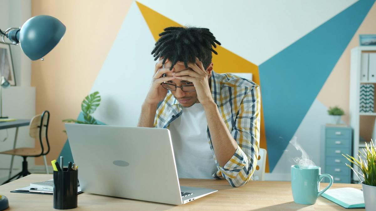 Endless loop of stressed Afro-American man employee thinking about project looking at laptop screen in office while steam raising from hot cup on table.