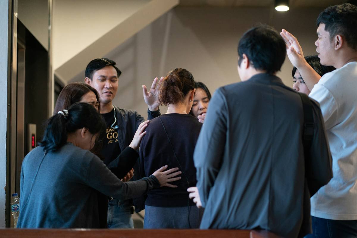 Group of people praying around a woman