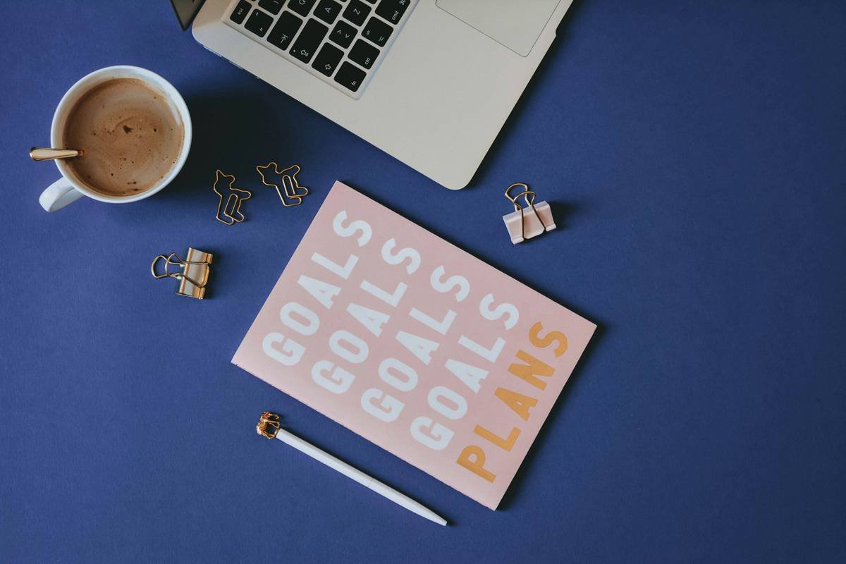 Pink planner on blue background with gold stationery and laptop ✦ Snag more FREE stock photos each month 👉 https://contentpixie.com/secret-snaps/